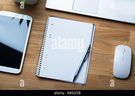 High angle view of notepad and pen with technologies on office desk Stock Photo