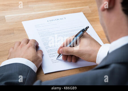 Cropped image of businessman signing contract document at office desk Stock Photo