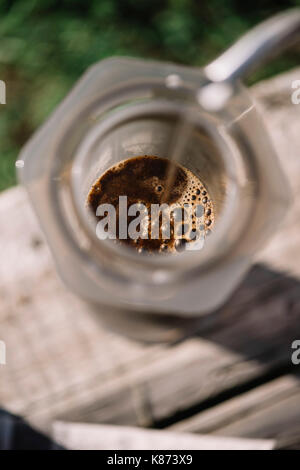 Fresh morning aeropressed coffee being brewed outdoor on the old wooden table background Stock Photo