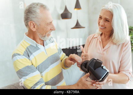 Positive retired couple holding VR glasses Stock Photo