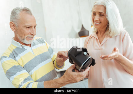 Positive aged coupel holding virtual reality glasses Stock Photo