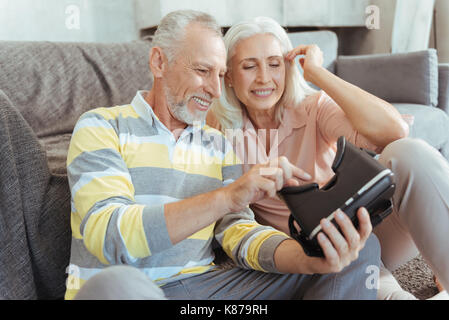 Positive aged couple trying up virtual reality device Stock Photo