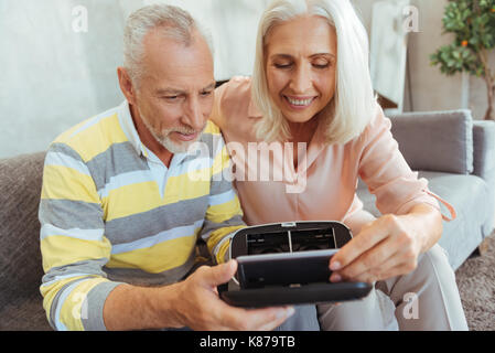 Cheerful retired couple putting smart phone inside of VR glasses Stock Photo