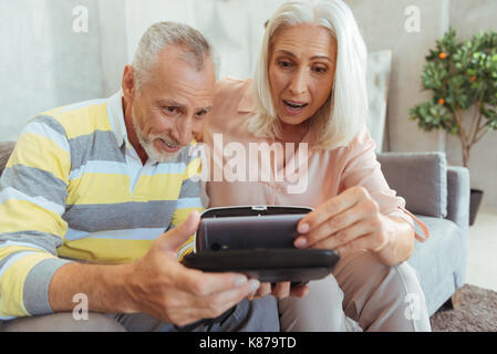 Surprised aged couple putting their smart phone inside the vr device Stock Photo