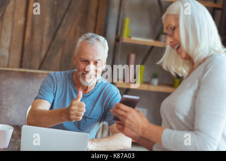 Positive elderly woman showing her husband a smart phone Stock Photo