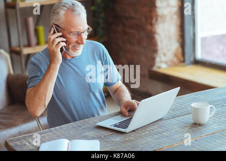 Joyful elderly man talking on phone Stock Photo