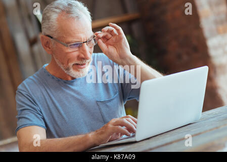 Concentrated aged man using laptop at home Stock Photo