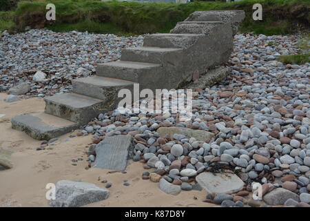 Concrete formed steps stairs on sandy pebble beach leading no where due to coastal erosion poor maintenance at Rosemarkie in Scotland Stock Photo