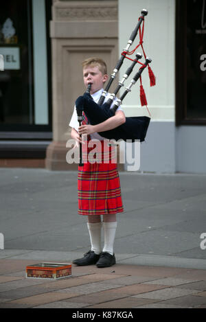 young boy child piper kilted royal  Stewart tartan  busker musician on Buchanan street Glasgow Scotland  the style mile biscuit tin Stock Photo