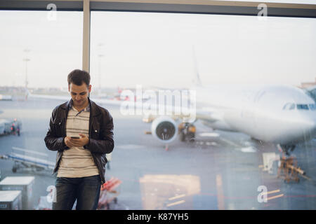 Young business man in airport using smartphone . Stock Photo