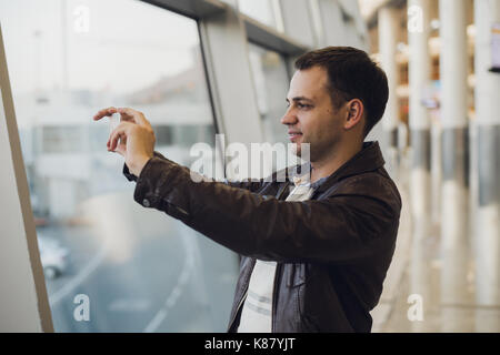 Young business man in airport using smartphone . Stock Photo