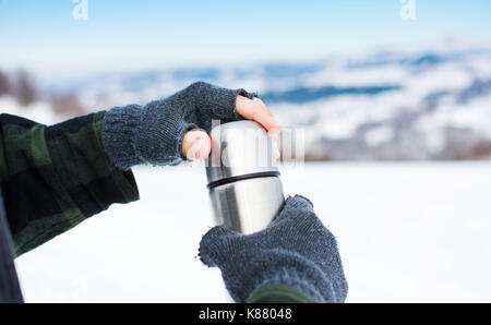 Man using thermos bottle on the snowy mountain Stock Photo