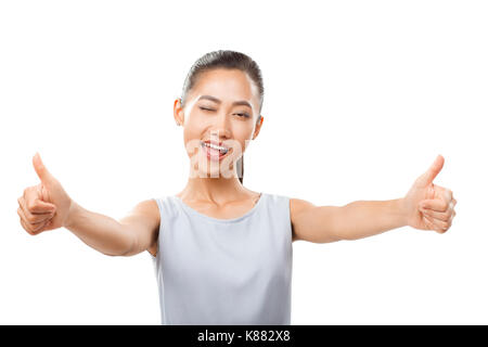 Portrait of half-body Asian woman with stretched hands showing thumbs up and winking. Playful emotional girl with positive facial expressions and agre Stock Photo