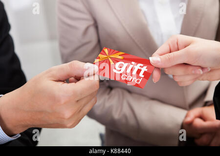 Close-up Of Businessperson Hands Giving Gift Card To Other Businessperson Stock Photo