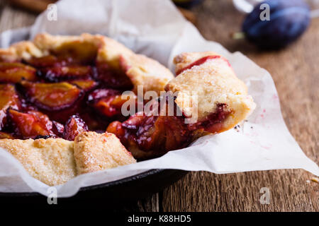 Fruit galette. Homemade rustic plum tart in cast iron skillet over country wooden background Stock Photo