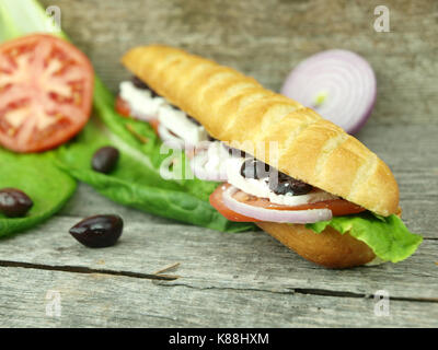 Mediterranean baguette with olives, feta cheese, onion, tomato and lettuce Stock Photo