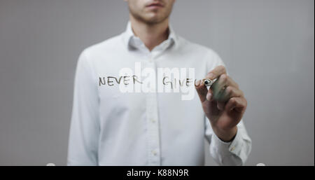 Never give up , Man Writing on Glass Stock Photo