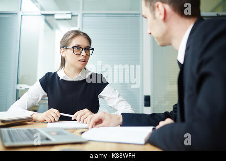 Group of talented young managers analyzing results of accomplished work while having working meeting at boardroom Stock Photo