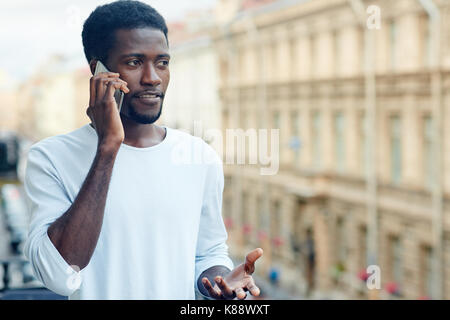 Busy guy in homewear speaking on smartphone on balcony Stock Photo