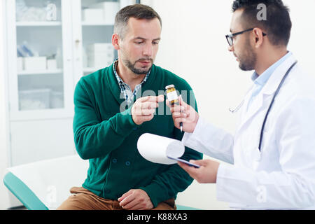 Doctor prescribing pills or vitamins to patient during medical consultation Stock Photo