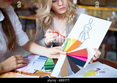 Two fashion designers choosing color for new model of dress from pantone chart Stock Photo