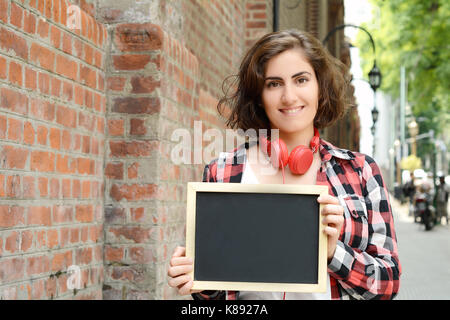 Portrait of a young beautiful woman holding chalkboard. Outdoors. Stock Photo