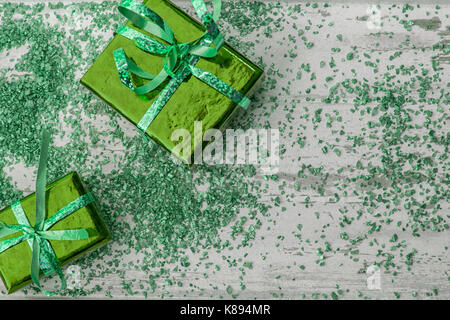 Holiday concept with green gift boxes and green sparkles on a  wooden background Stock Photo