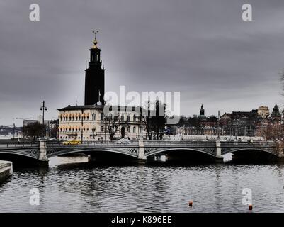 A yellow car on the Vasabron bridge over Norrstrom, with Stockholm's City Hall, including the iconic tower, in the background. Stock Photo