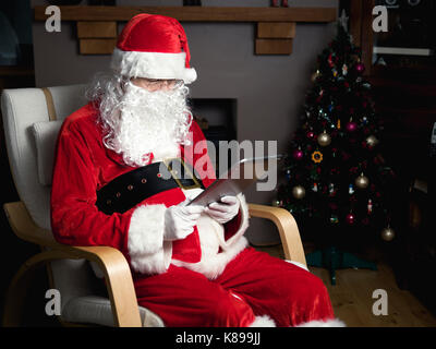Santa claus Using Mobile Tablet Computer in home Stock Photo