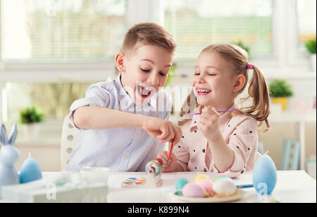 Two happy children having fun during painting eggs for easter in spring time Stock Photo