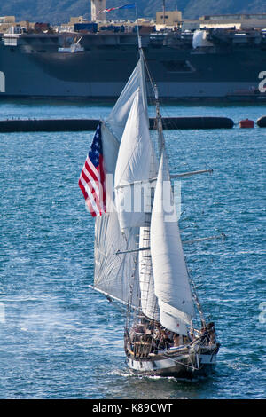 Tall Sailing Ship Anazing Grace under full sail on San Diego Bay, CA US fires cannons during naval battle with aircraft carrier in background  Amazing Stock Photo
