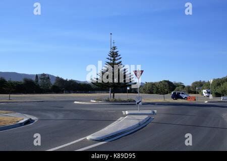 Traffic roundabout in Australian city of Coffs Harbour. In view are trees and vehicles. Stock Photo