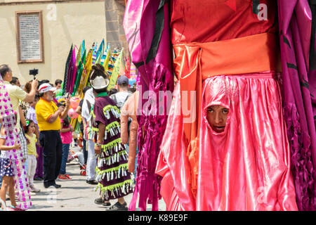 A puppeteer looks out from a small hole in the costume of a giant papier mâché puppets called mojigangas during a children's parade celebrating Mexican Independence Day celebrations September 17, 2017 in San Miguel de Allende, Mexico. Stock Photo