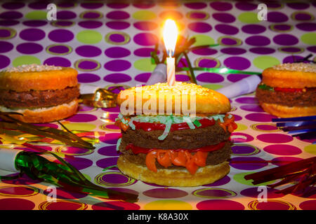 Dessert impostor mock double cheeseburger, cheeseburger and hamburger with vanilla cupcake bun and brownie burger on purple polka dot paper with color Stock Photo