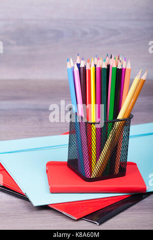 School and office supplies on a wooden background. On the table there are wooden crayons of different colors, notes and folders. Copy space Stock Photo