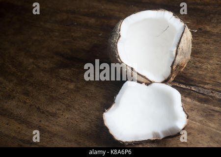 Closeup of ripe half coconut isolated on wooden table background Stock Photo