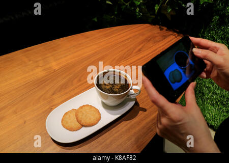 Woman's Hand Taking Picture of Coffee and Cookies with Cell Phone in the Coffee Shop Stock Photo
