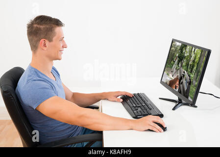 Happy Man Playing Game On Desktop Computer At Desk Stock Photo