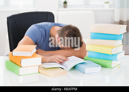 Young Man With Books Sleeping At Desk Stock Photo