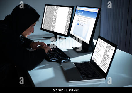 Male Hacker Using Computers To Steal Data In Office Stock Photo
