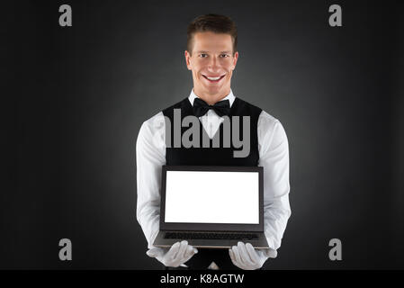 Portrait Of Happy Waiter Showing Blank Display Laptop Stock Photo