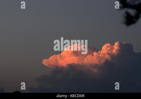 Cumulus cloud turns red at sunset Stock Photo