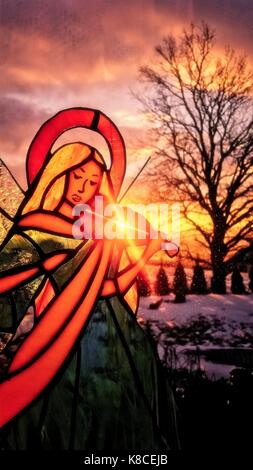 An angel playing the violin. Stained glass angel. Winter background. Colorful scenery. Sun shining through the stained glass. Stock Photo