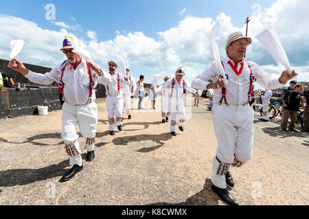 Hartley Morris dancers in all white shirt and trousers, red braces and straw hats, dancing waving white hankies at Broadstairs harbour. Daytime. Sunny. Stock Photo