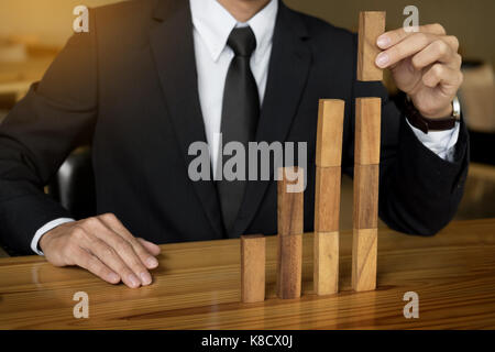 Concept growing value. hand of businessman pick up a wood block like bar graph growth Stock Photo