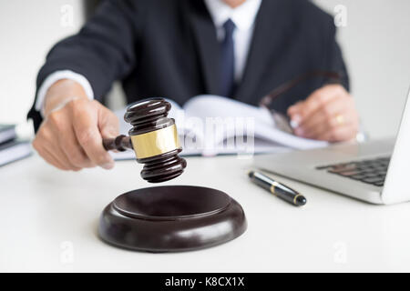 Male Judge lawyer In A Courtroom Striking The Gavel on sounding block. Stock Photo