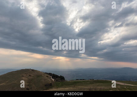 View of a valley from a mountain, with sun rays coming out through the clouds Stock Photo