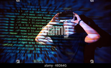 Double exposure of a caucasian man and Virtual reality headset is presumably a gamer or a hacker cracking the code into a secure network or server, with lines of code Stock Photo