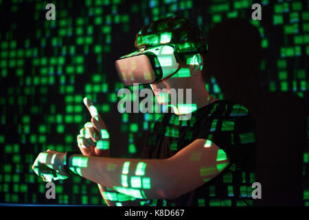 Double exposure of a caucasian man and Virtual reality headset is presumably a gamer or a hacker cracking the code into a secure network or server, with lines of code Stock Photo