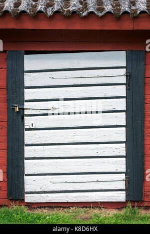 Closed white barn door on red and black barn. Stock Photo